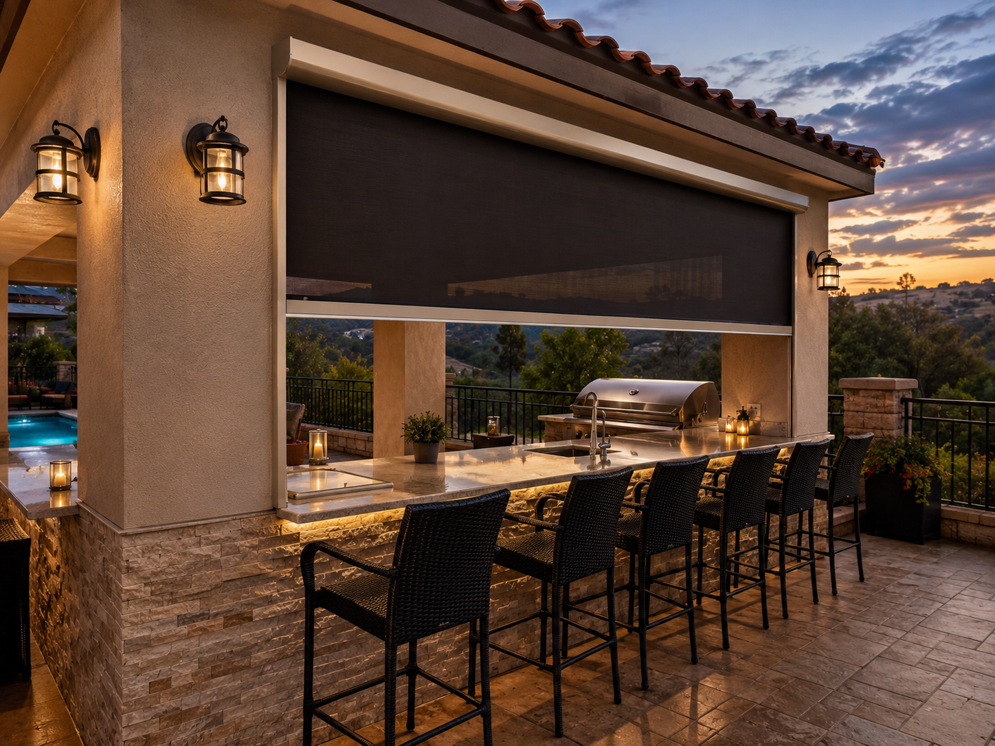 Motorized power screen lowered over an outdoor kitchen bar at dusk