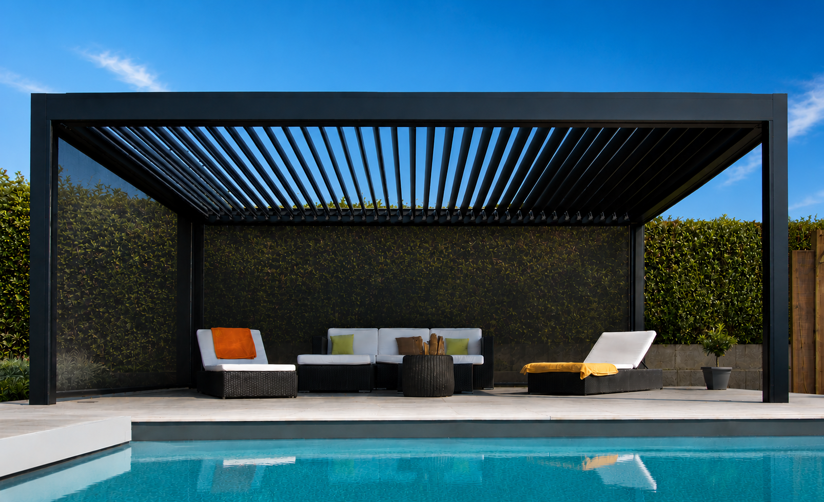 Black louvered pergola over a poolside lounge in full sun